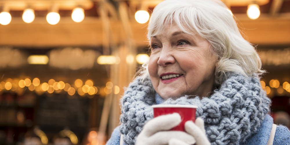 Happy mature lady warming up by hot beverage outdoor